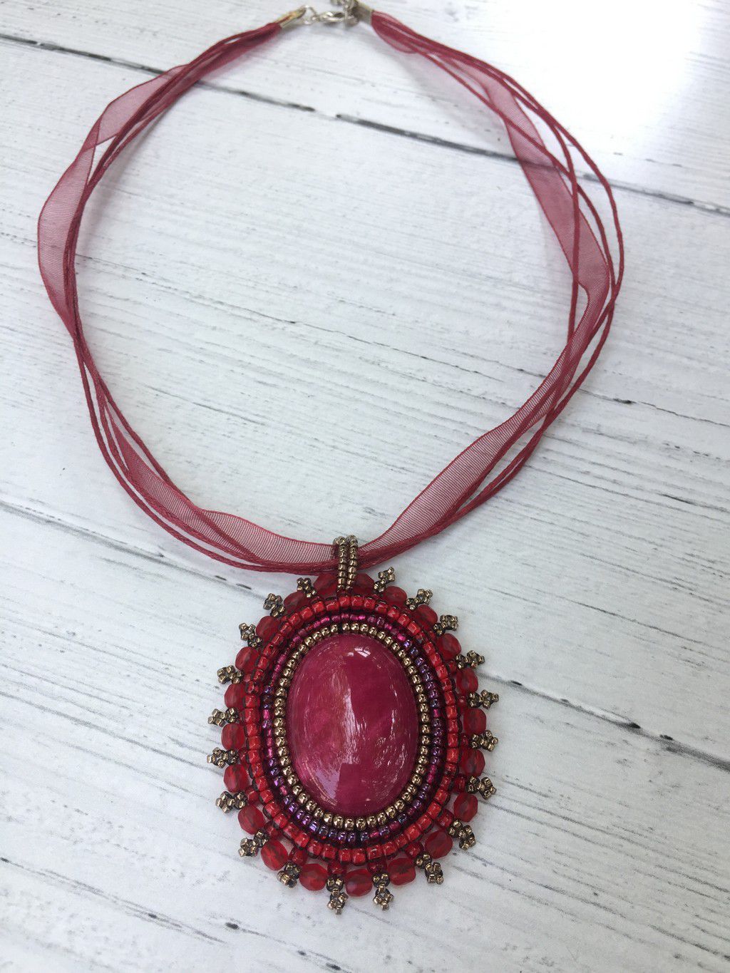 Stunning oval red jasper pendant on triple silk cord wih red and gold beaded bezel
