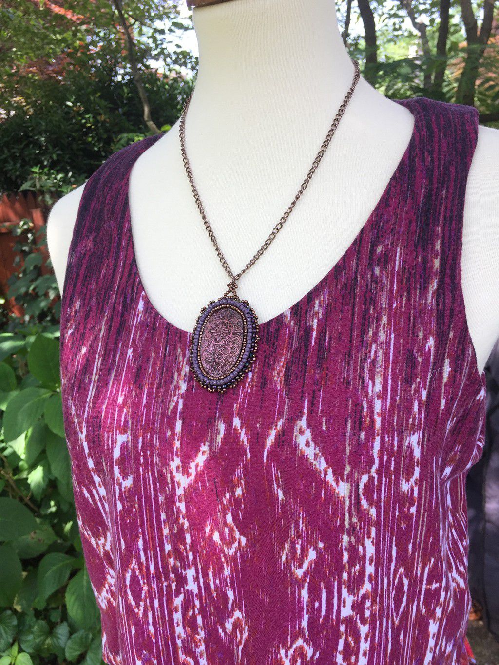Dark pink oval floral necklace on a model with magenta dress.