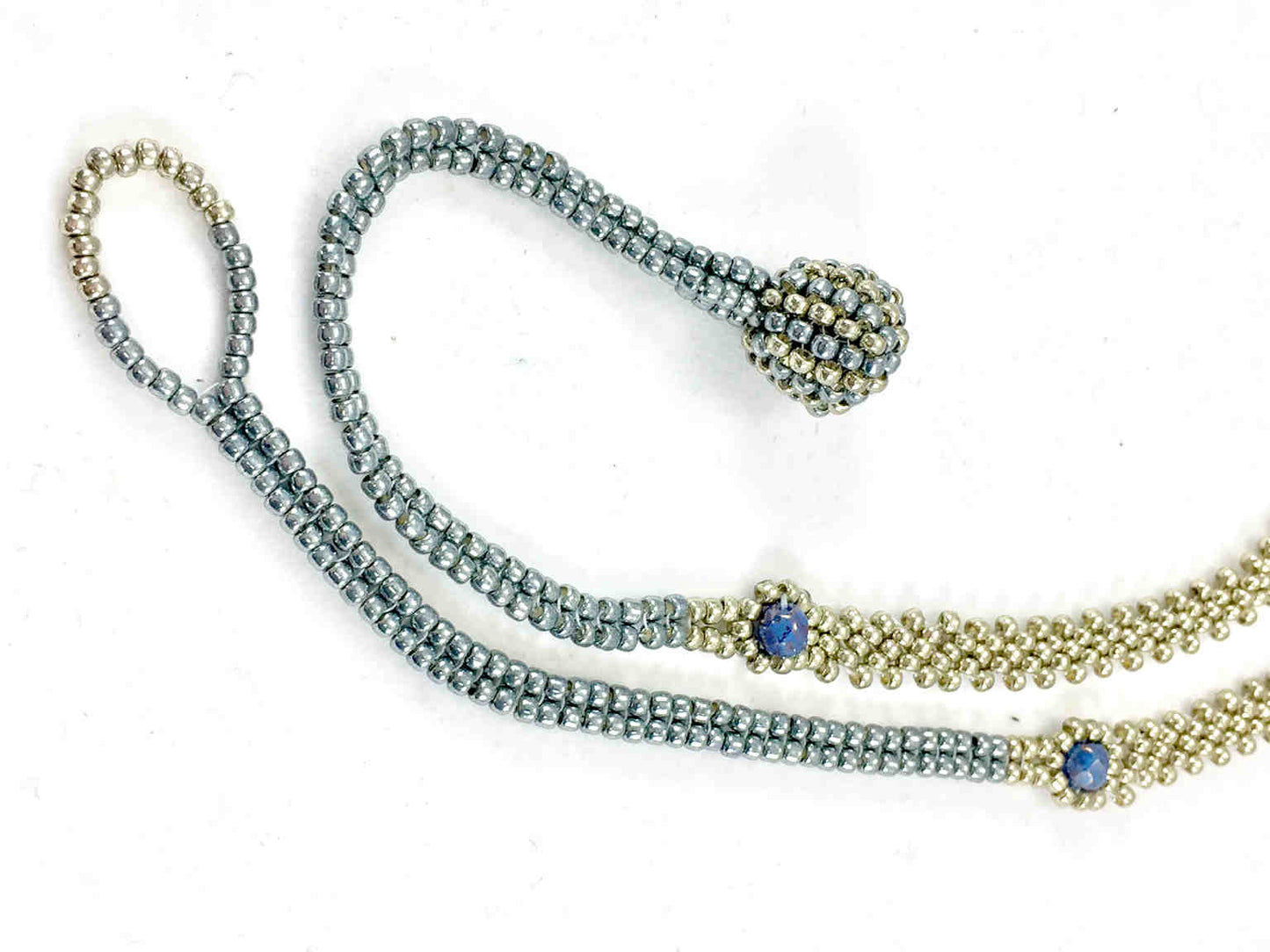 Close up of silver seed bead chain with blue crystals and ball and loop closure