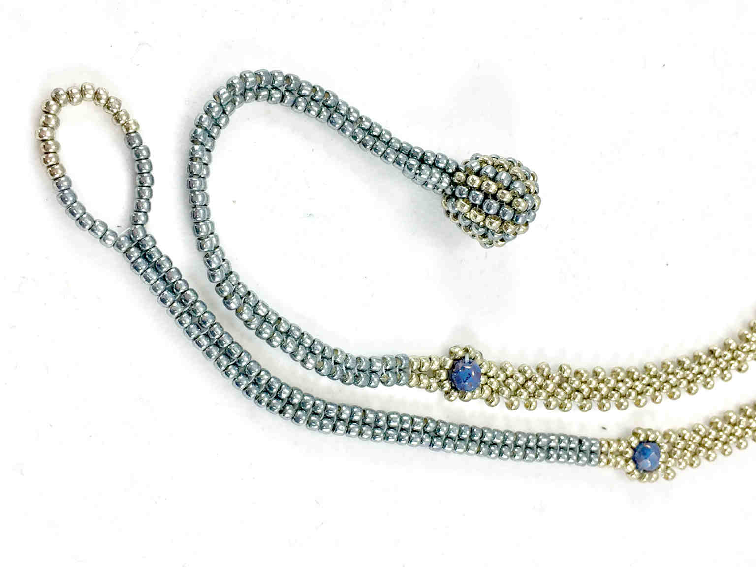 Close up of silver seed bead chain with blue crystals and ball and loop closure