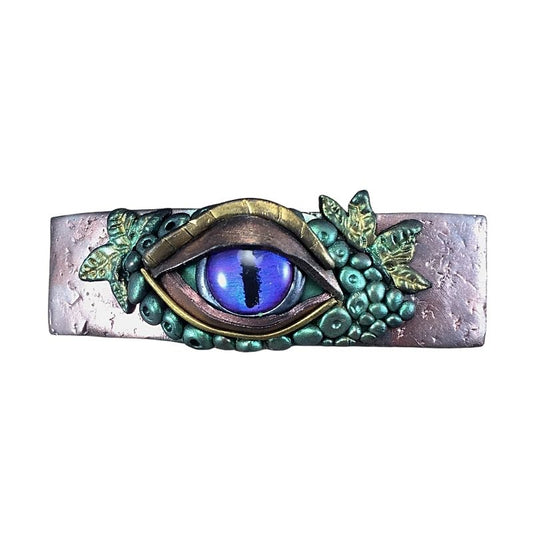 An all seeing eye hair barrette in purple, gold and green hand painted polymer clay