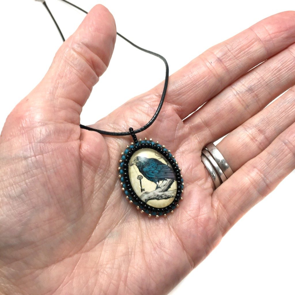 blue raven pendant in hand