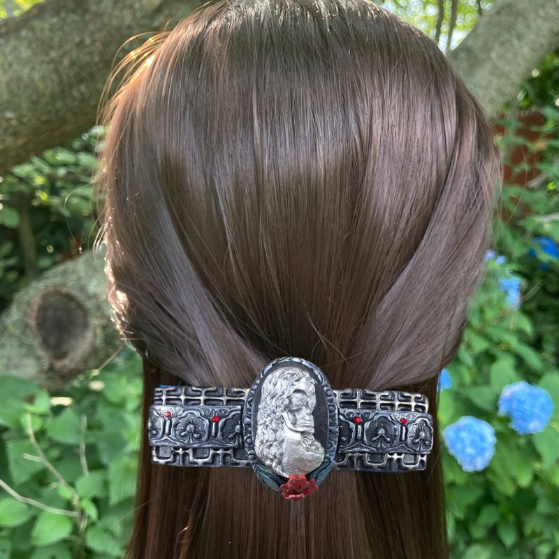 silver skeleton cameo polymer clay hair barrette with red flowers and red crystals with a black textured base highlighted silver on a model.