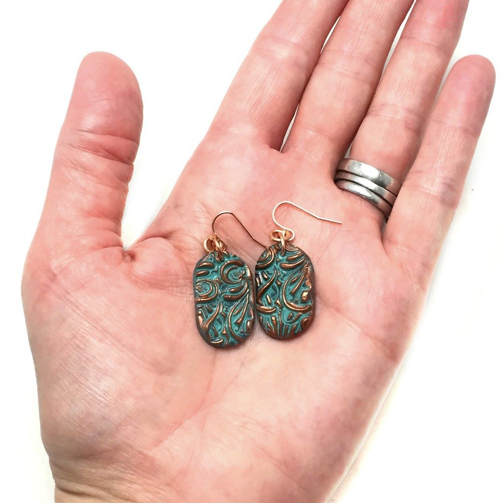 Floral copper patina earrings in hand