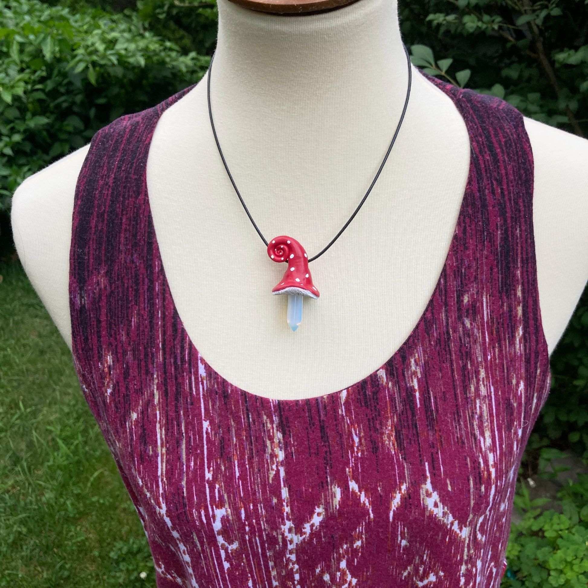 Polymer clay red mushroom necklace with black cord on model 