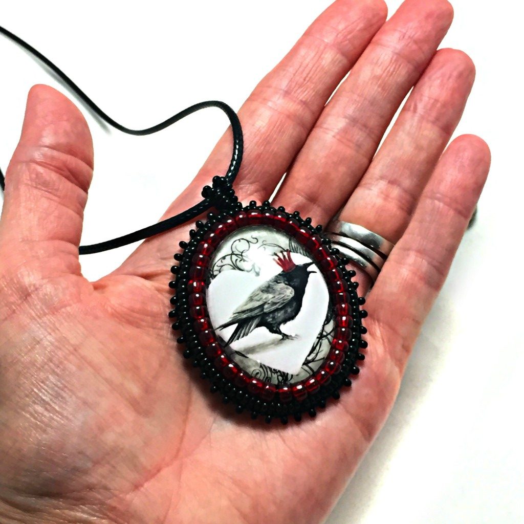 red crown raven pendant in hand