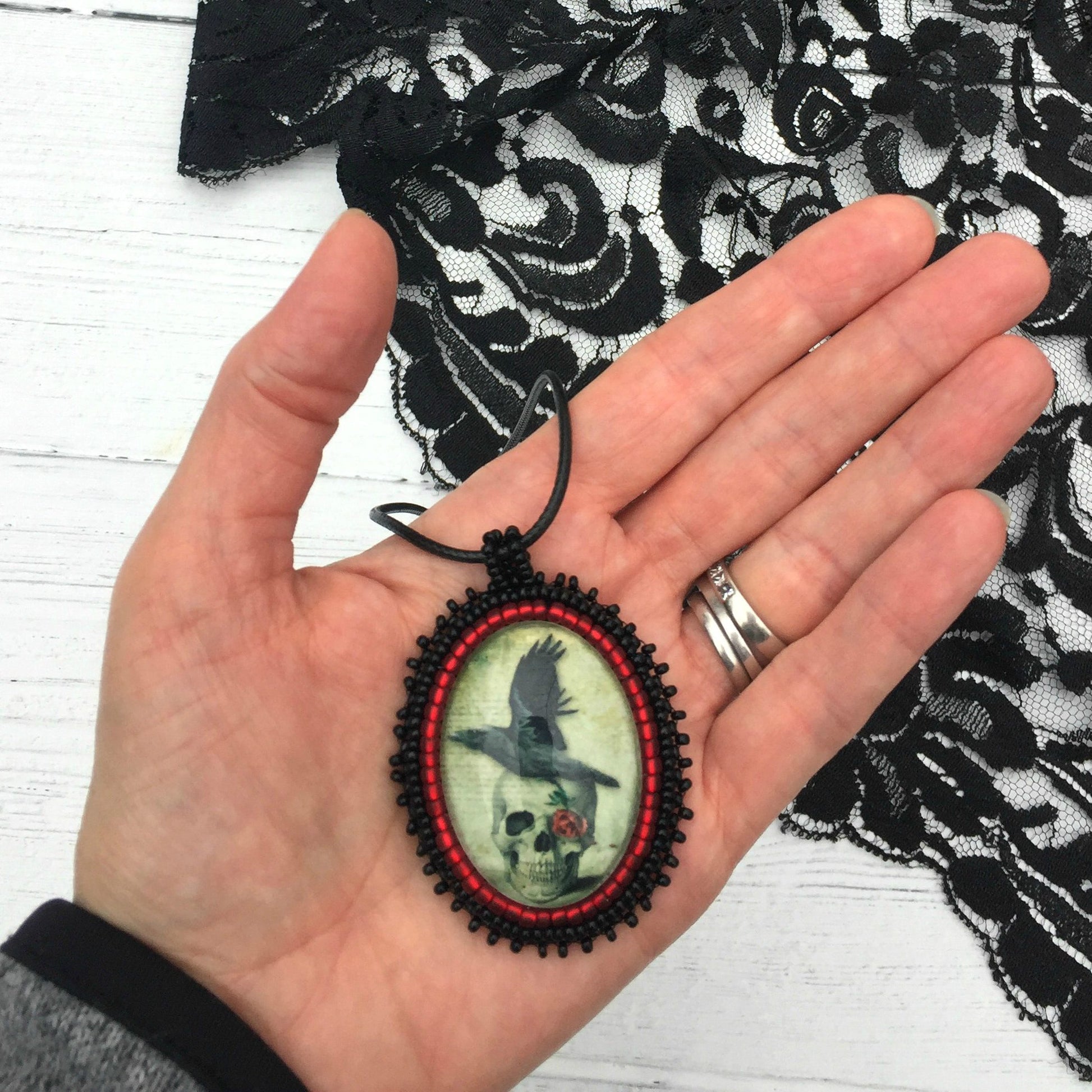 raven and skull pendant in hand