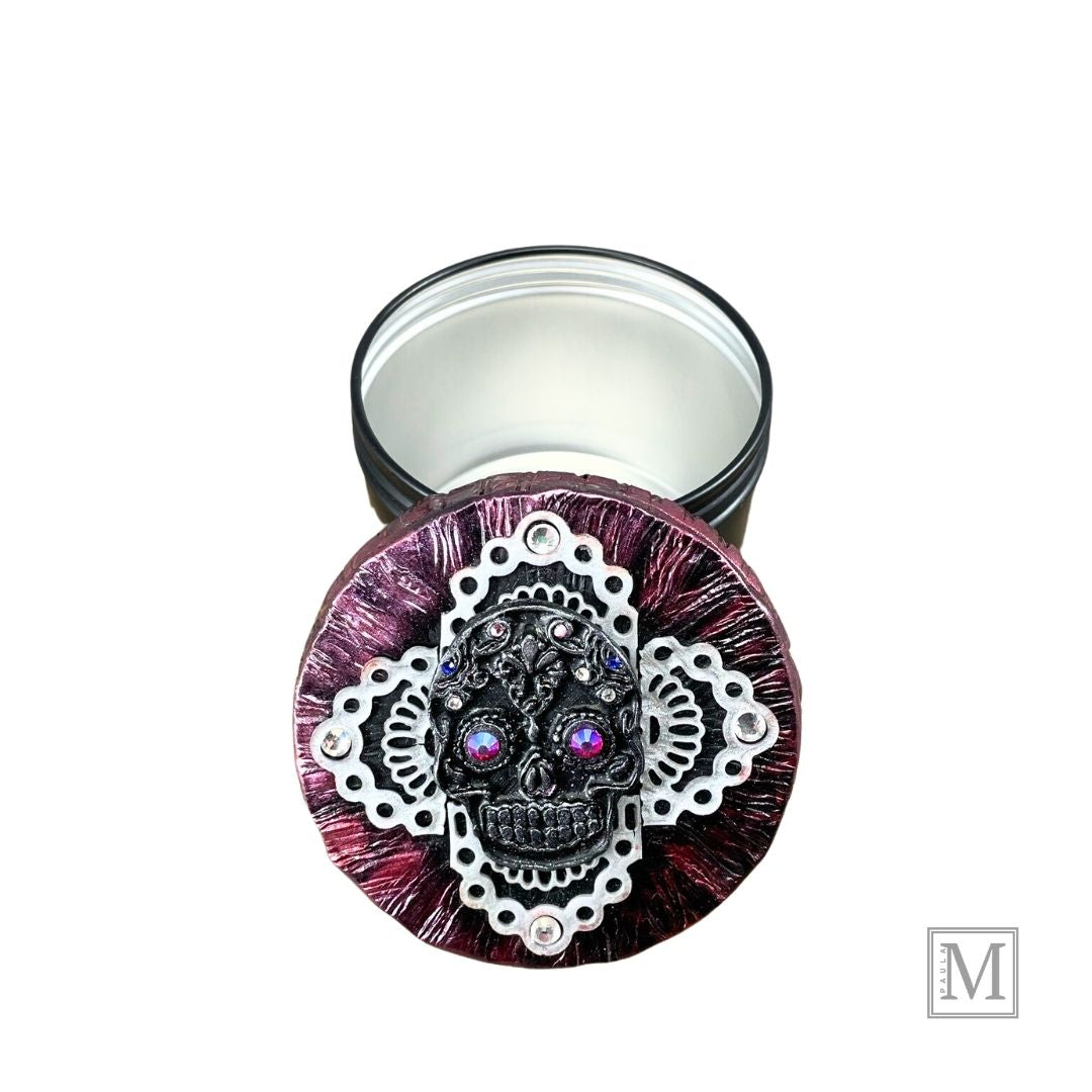 Black and Silver Sugar Skull with pink luster crystal eyes and colred small crystal details on a clay lace cross overlay with a deep metallic clay covered lid. Lid is propped up against black base of tin.