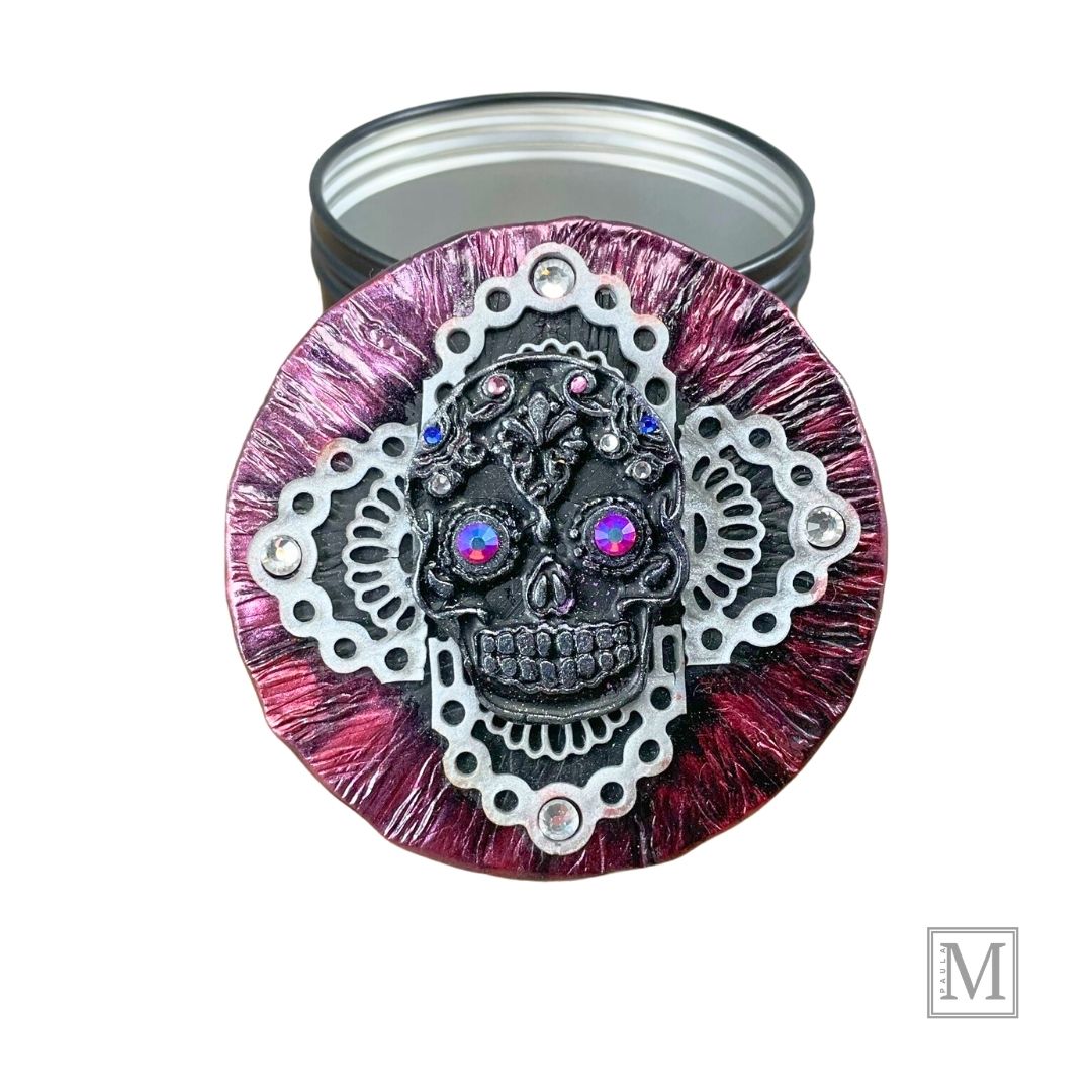Black and Silver Sugar Skull with pink luster crystal eyes and colred small crystal details on a clay lace cross overlay with a deep metallic clay covered lid. Lid is propped up against black base of tin