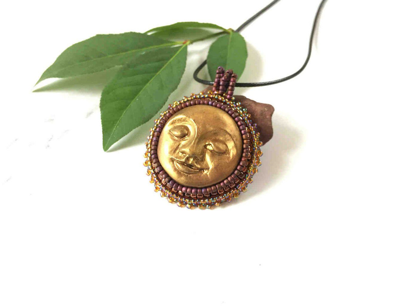 sun face round pendant in gold with burgandy and iradescent beaded bezel