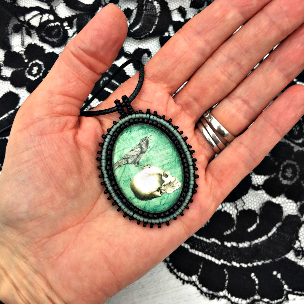 turquoise raven skull pendant in hand