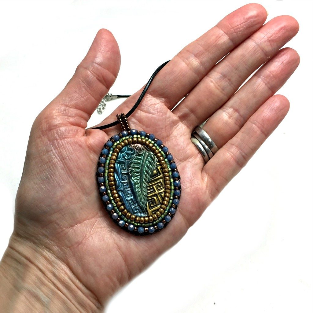 zentangle art pendant with blue crystals in hand