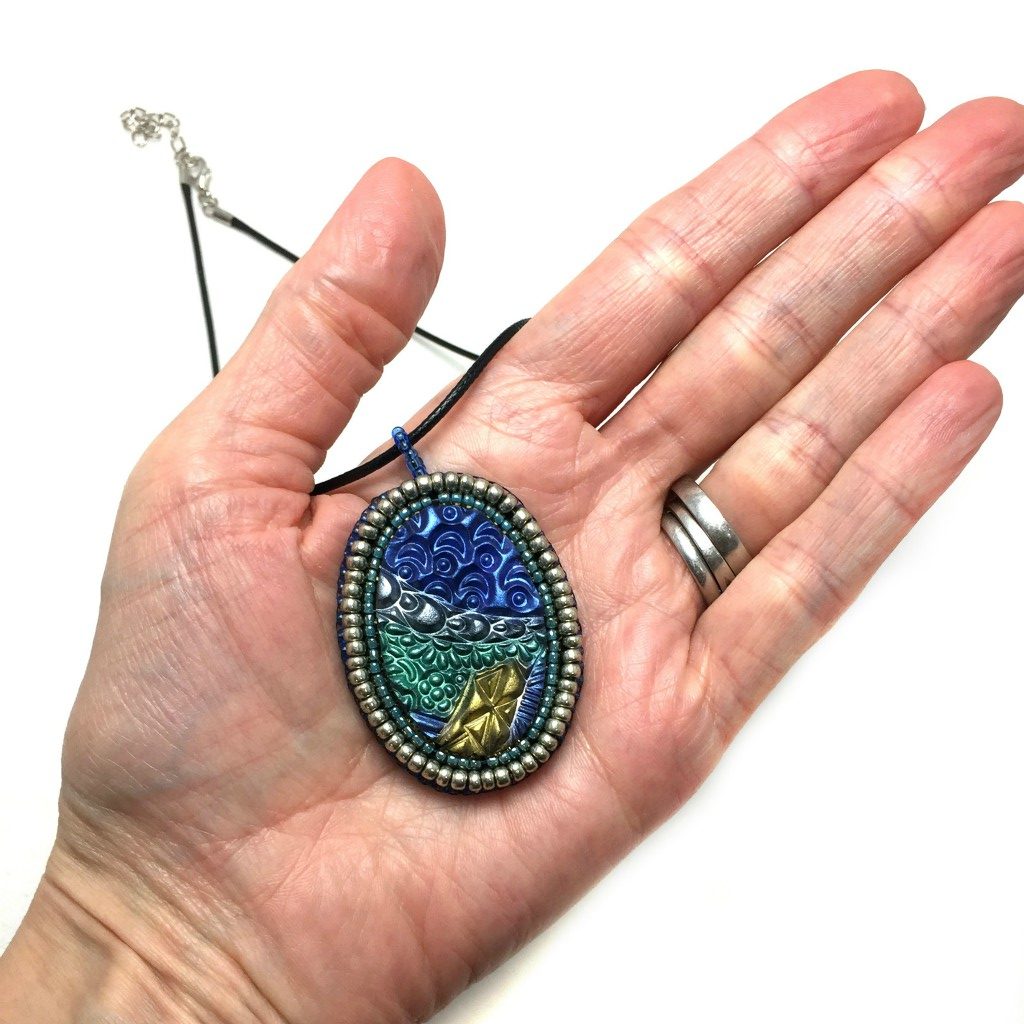 zentangle pendant with silver edge in hand